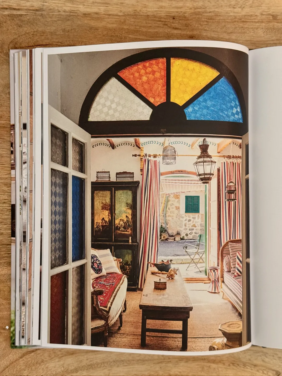 Stained-glass fanlight above doors opening onto a sunlit eclectic room