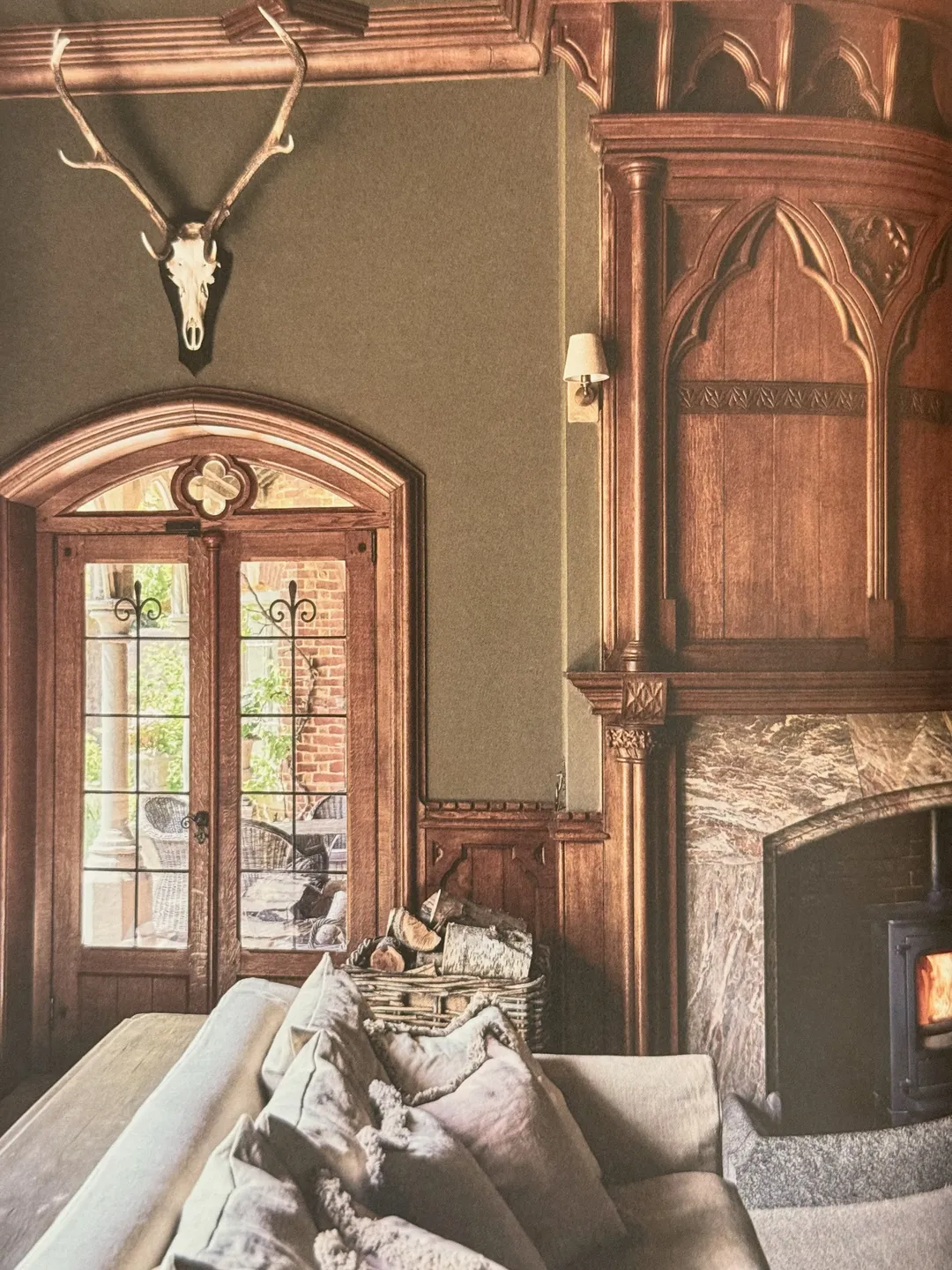 Gothic wood-panelled room with antlers, a carved doorway and a fireplace