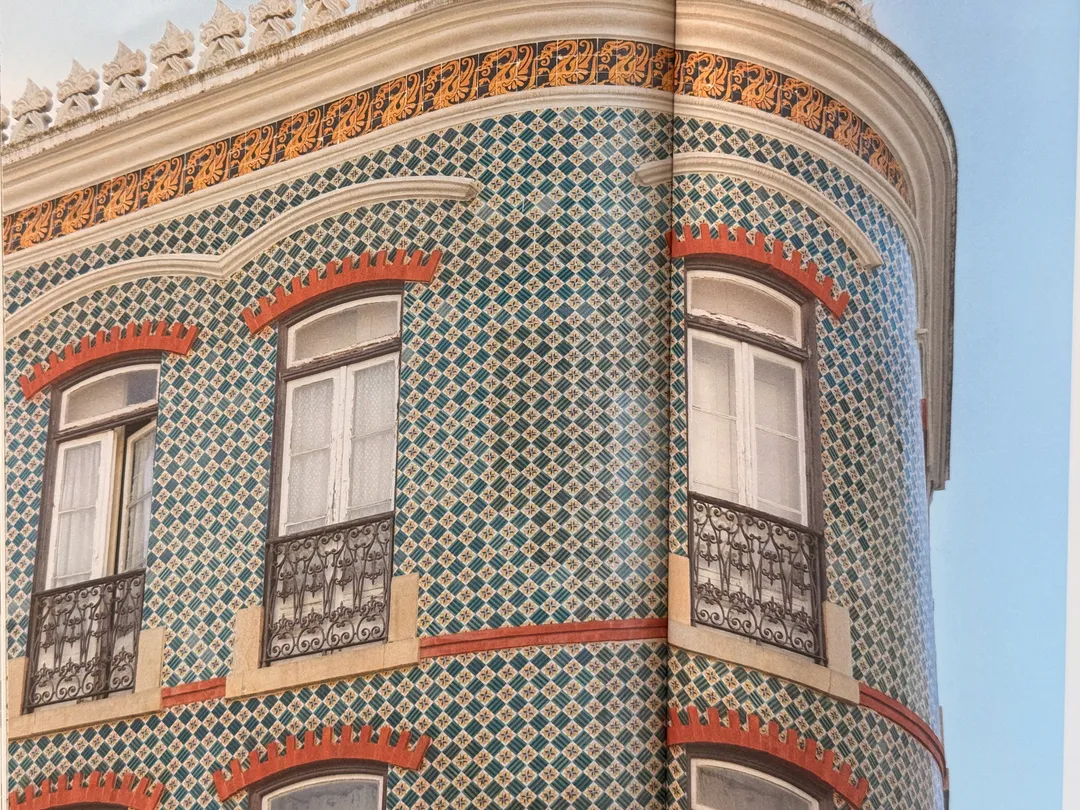 Facade covered in patterned azulejo tiles with terracotta window trims, from Patterns of Portugal by Christine Chitnis