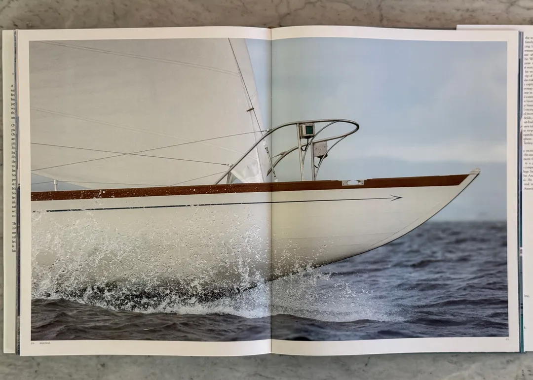 Varnished bow of a classic yacht slicing through a wave