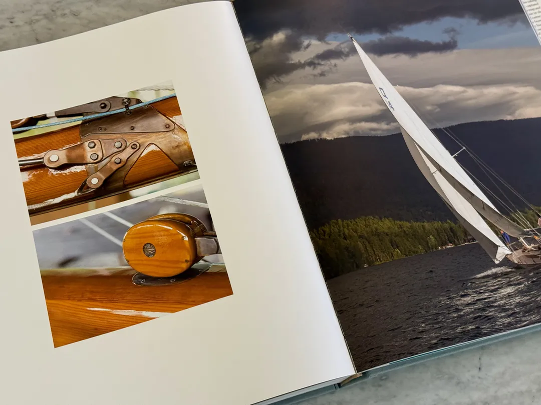 Brass winch and teak details, and a sailboat under a stormy sky