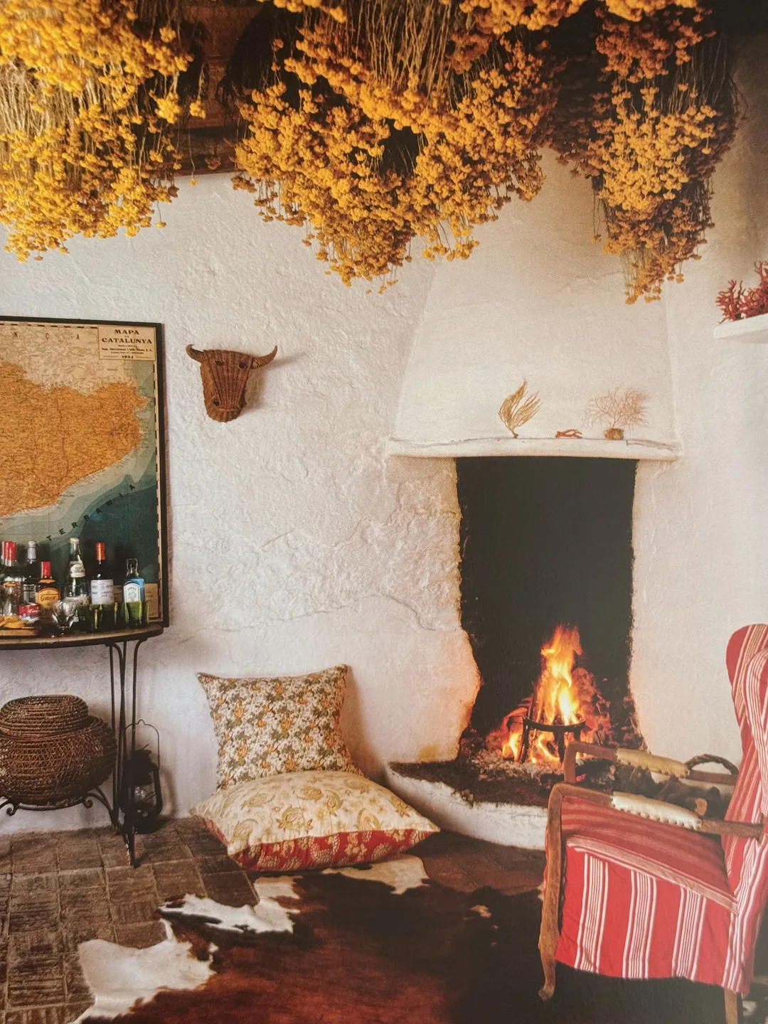 Whitewashed sitting room with a corner fireplace, dried flowers hanging from the beams