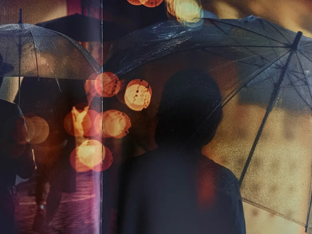 Silhouette behind a clear umbrella with blurred orange lights