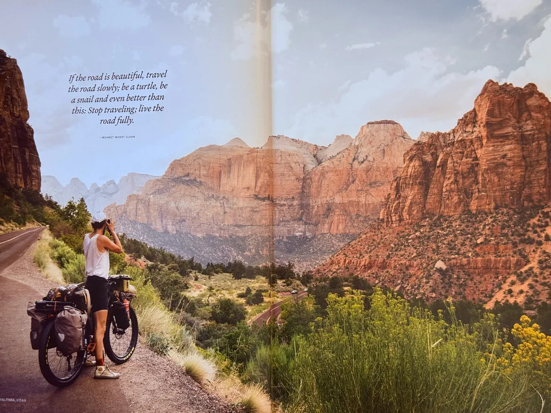 Cyclist with panniers pausing above a red-rock canyon