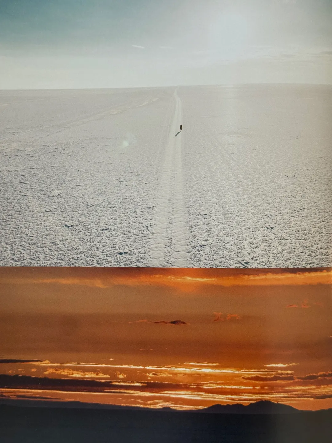 Lone tyre track across a vast salt flat, and a sunset over clouds