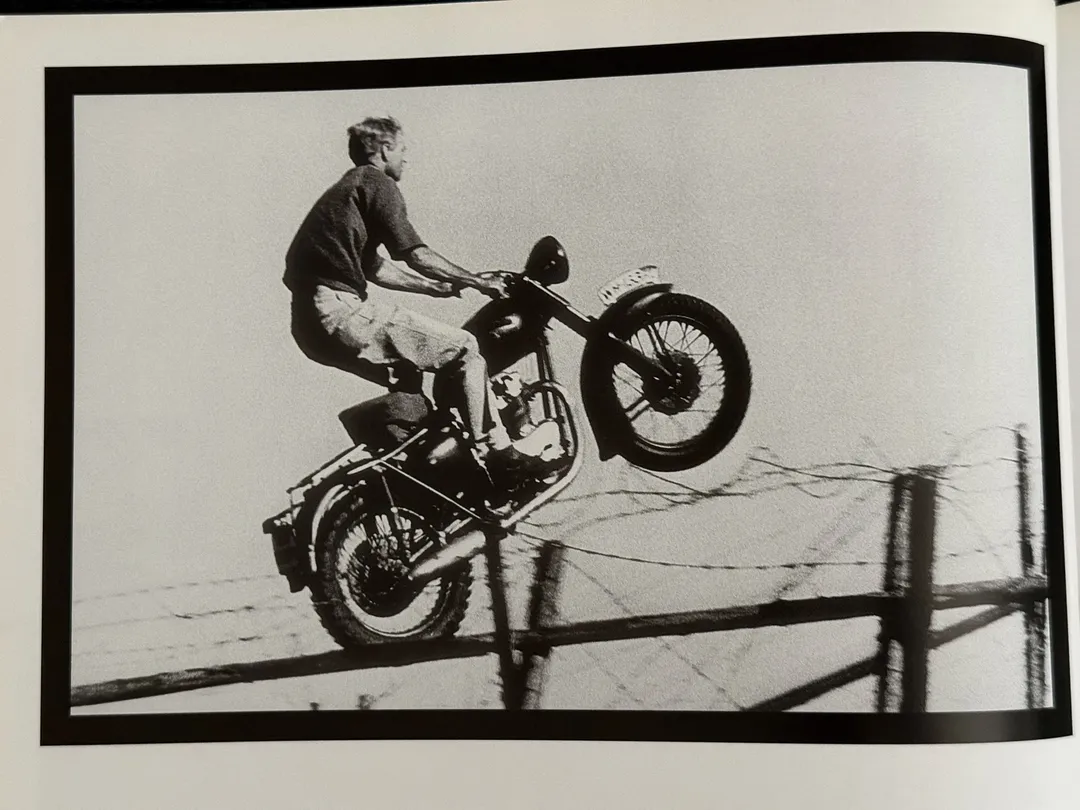 Motorcycle mid-jump over a barbed-wire fence