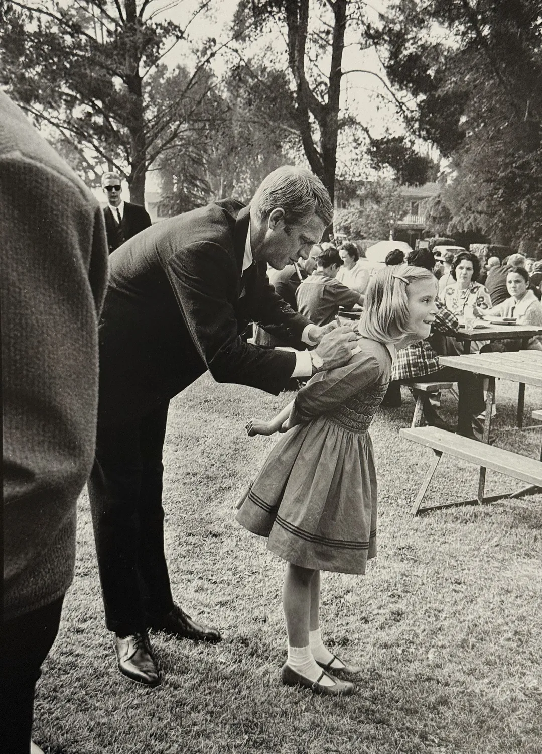 McQueen bending to talk with a young girl at a picnic